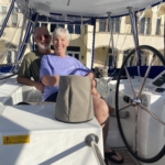 An elderly couple relaxing on a sailboat on a sunny day.