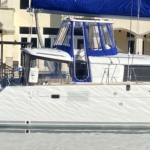 Sailboat docked with blue canopy and windows.