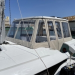 A boat with a protective beige canvas enclosure on a sunny day.
