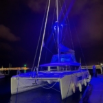 A catamaran docked at night with blue illumination.