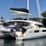 A sleek white catamaran yacht docked at the marina on a sunny day.