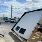 Man working on a large solar panel installation outdoors on a sunny day.