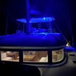 Boat illuminated with vibrant blue lights at night.