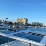 Boats docked at a marina under a clear blue sky near city buildings.