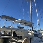 A white catamaran docked at a marina under clear blue skies.
